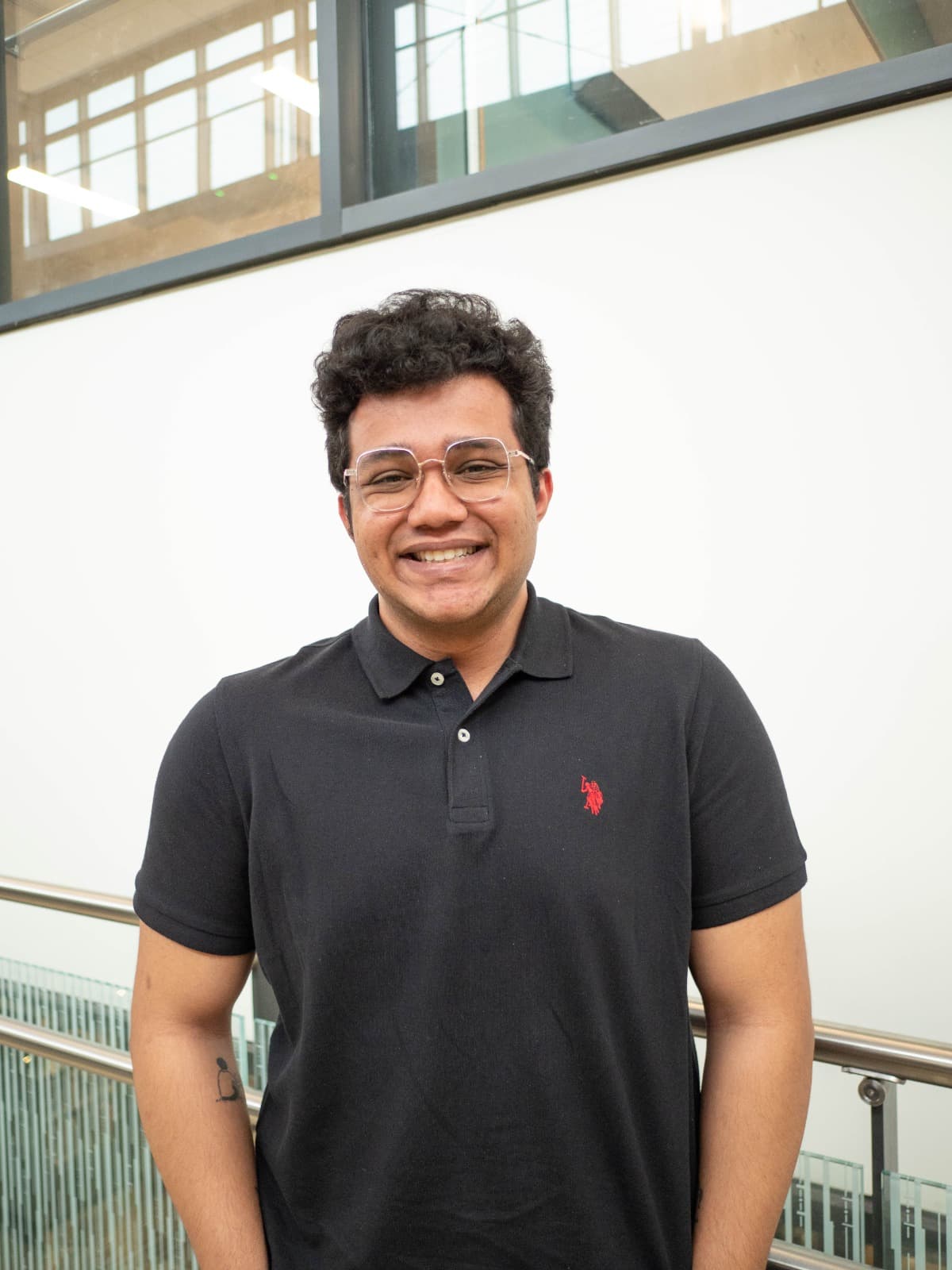 Pratyush smiling, wearing glasses and a black polo shirt